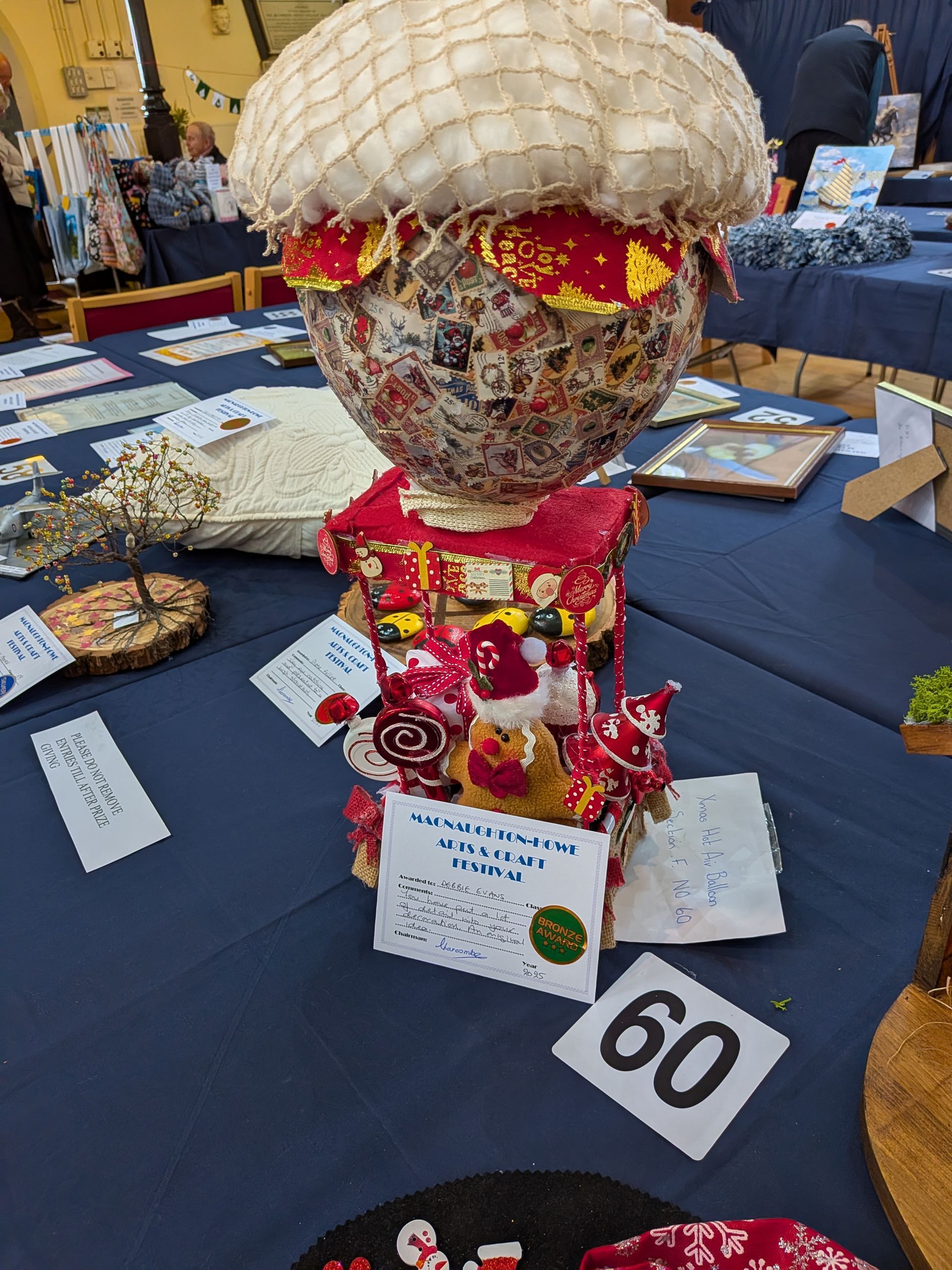A whimsical, decorated mushroom sculpture on a table with other crafts.