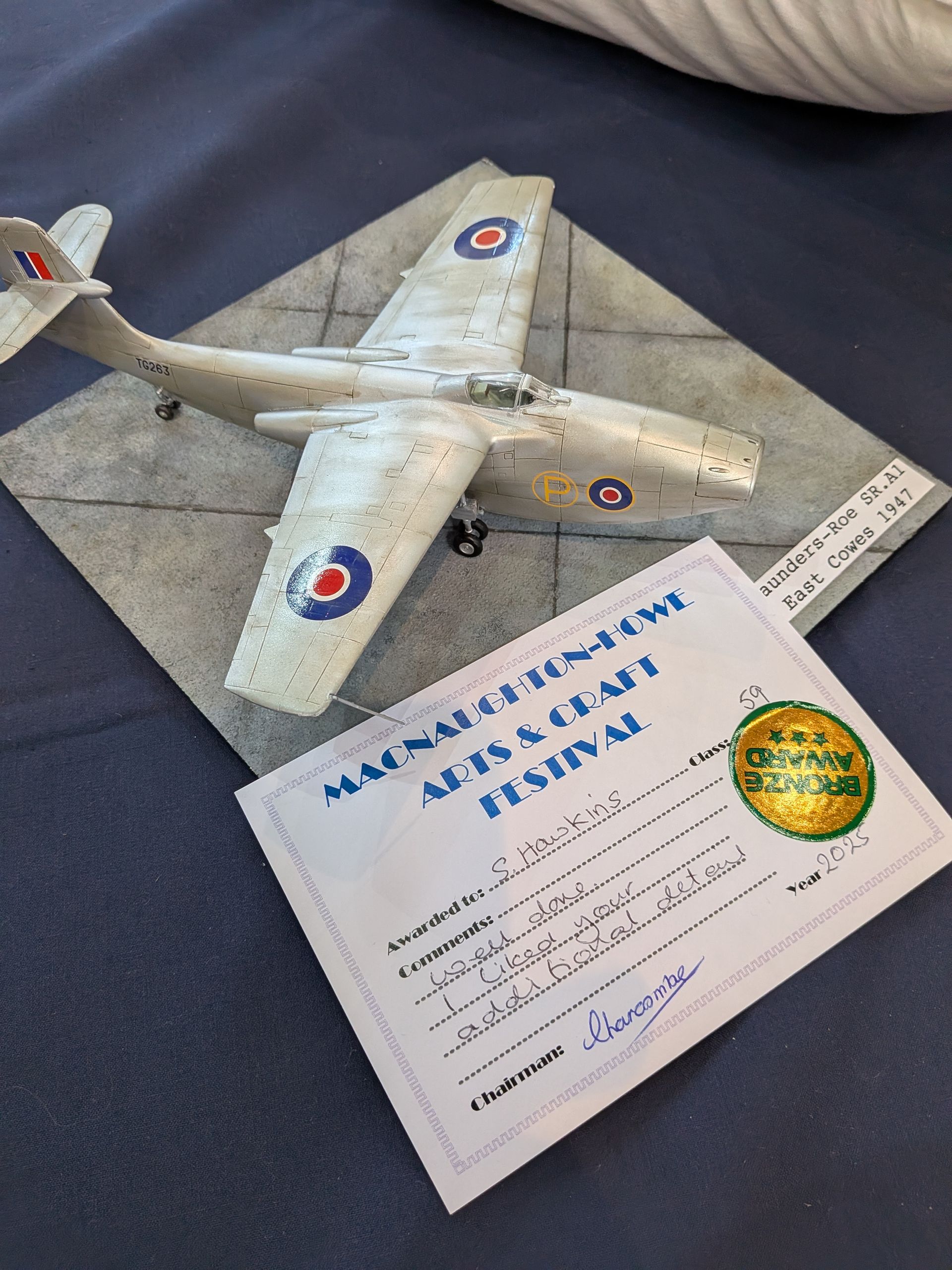 Model airplane with blue roundels on a gray surface, next to an award certificate.