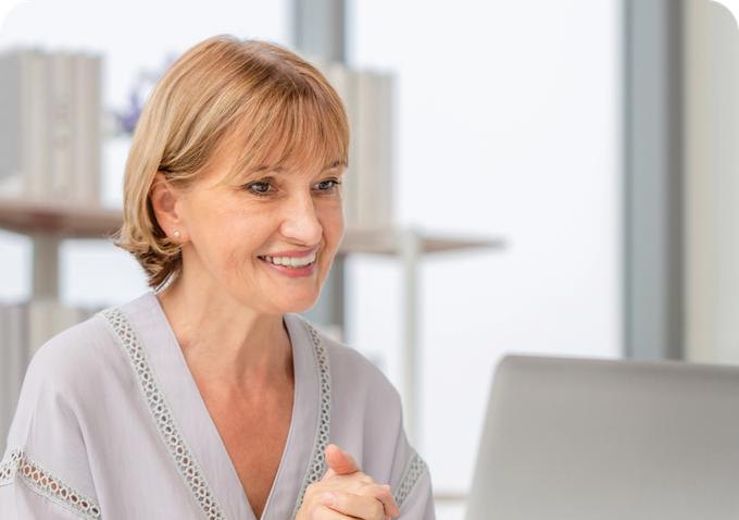 older woman talking to computer screen wearing gray blouse