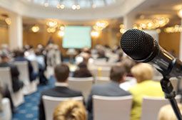 image of a microphone with an audience blurred in the background
