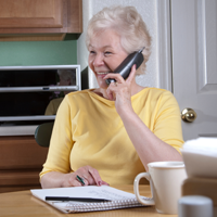 Elderly woman in yellow shirt talking on the phone