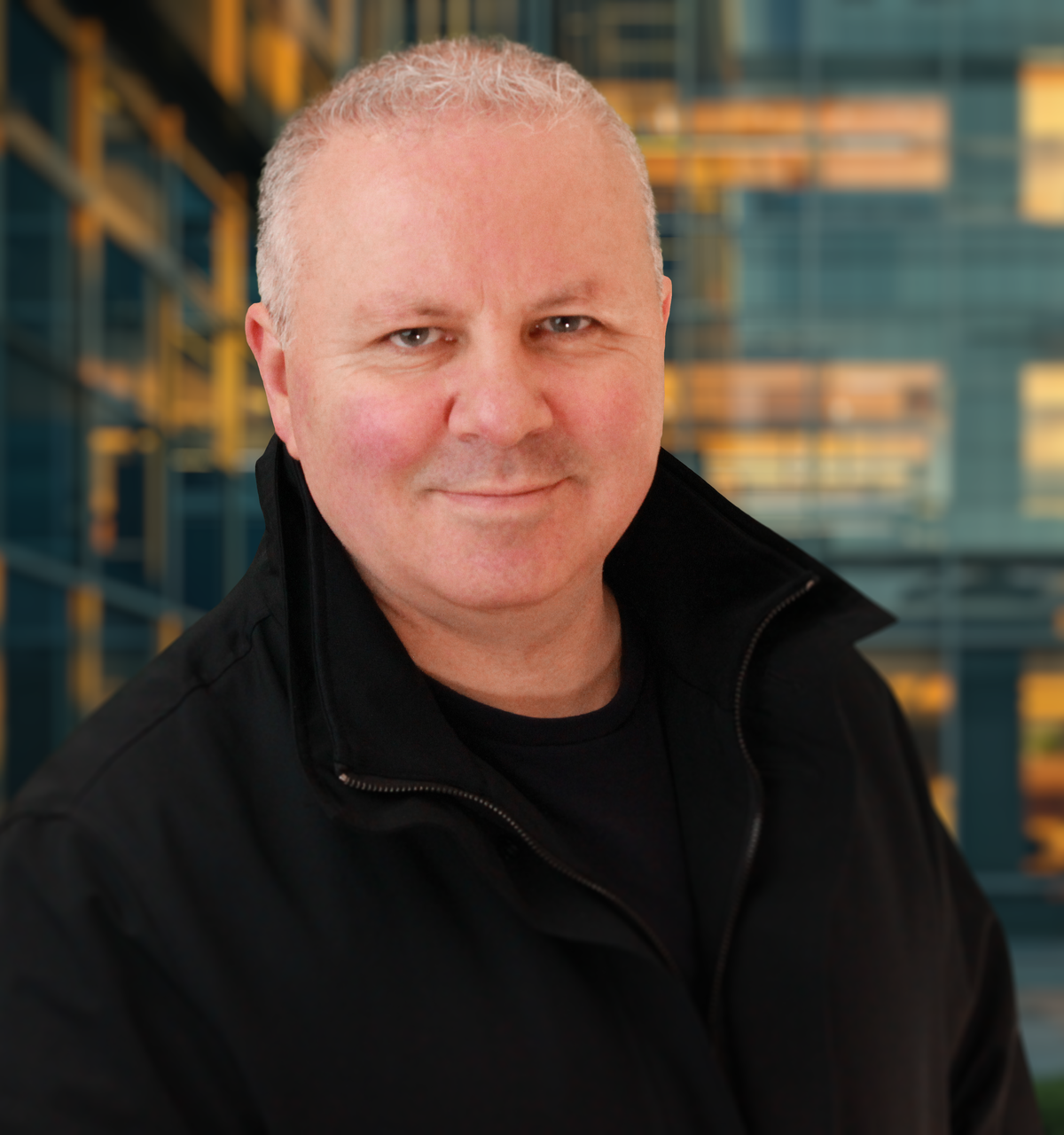 A man in a black jacket is smiling for the camera