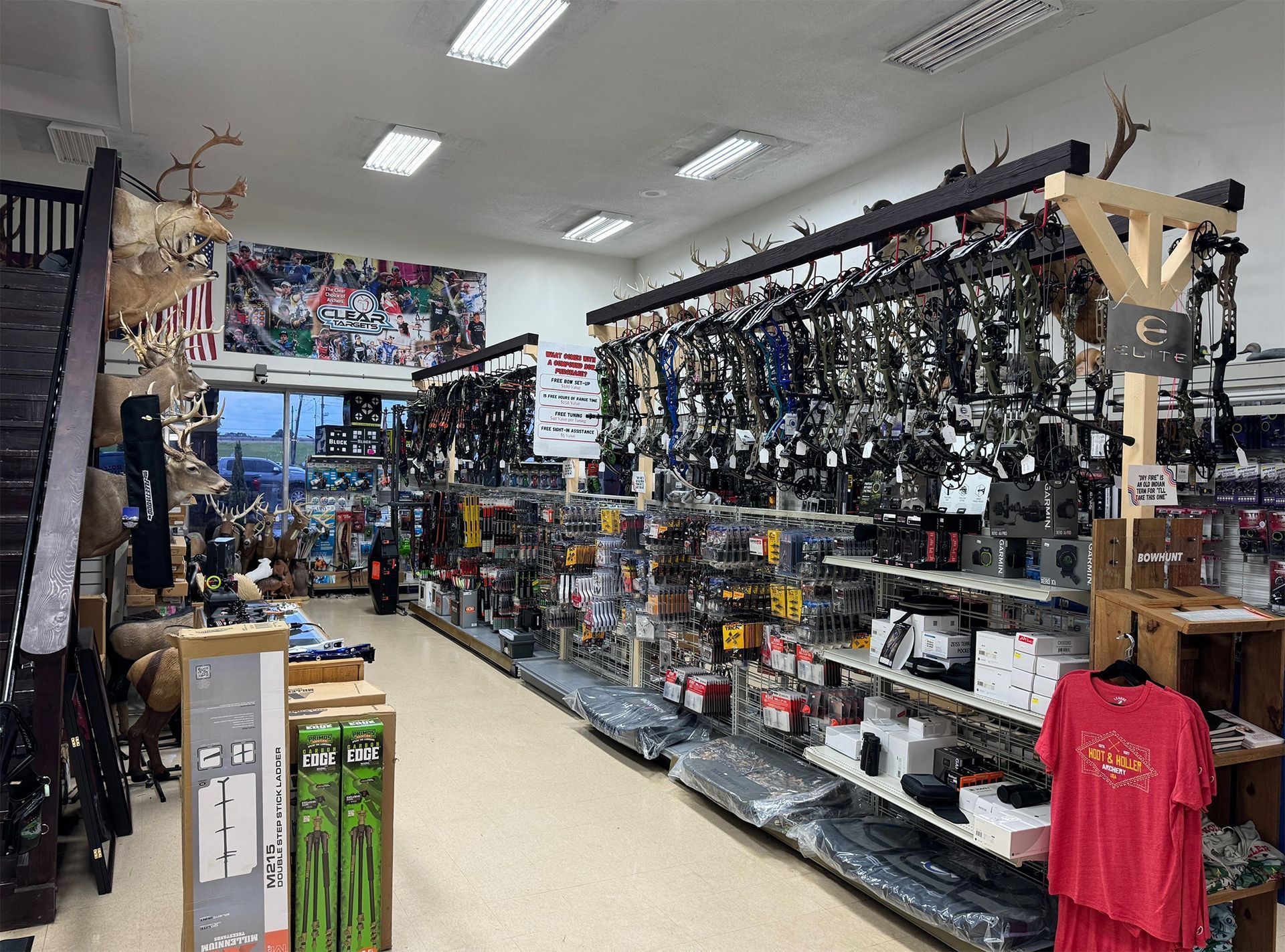 Narrow shop aisle filled with bike accessories, tools, and hanging gear under bright ceiling lights