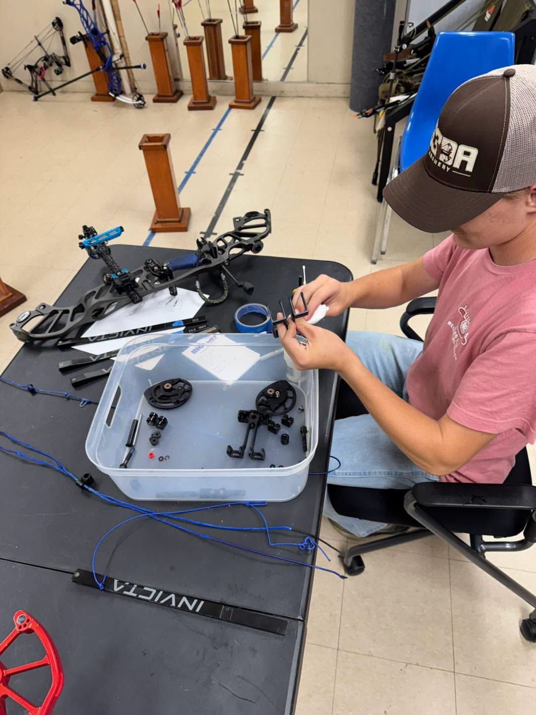 Person wiring a drone on a workbench in a robotics lab, with tools and drone parts nearby.