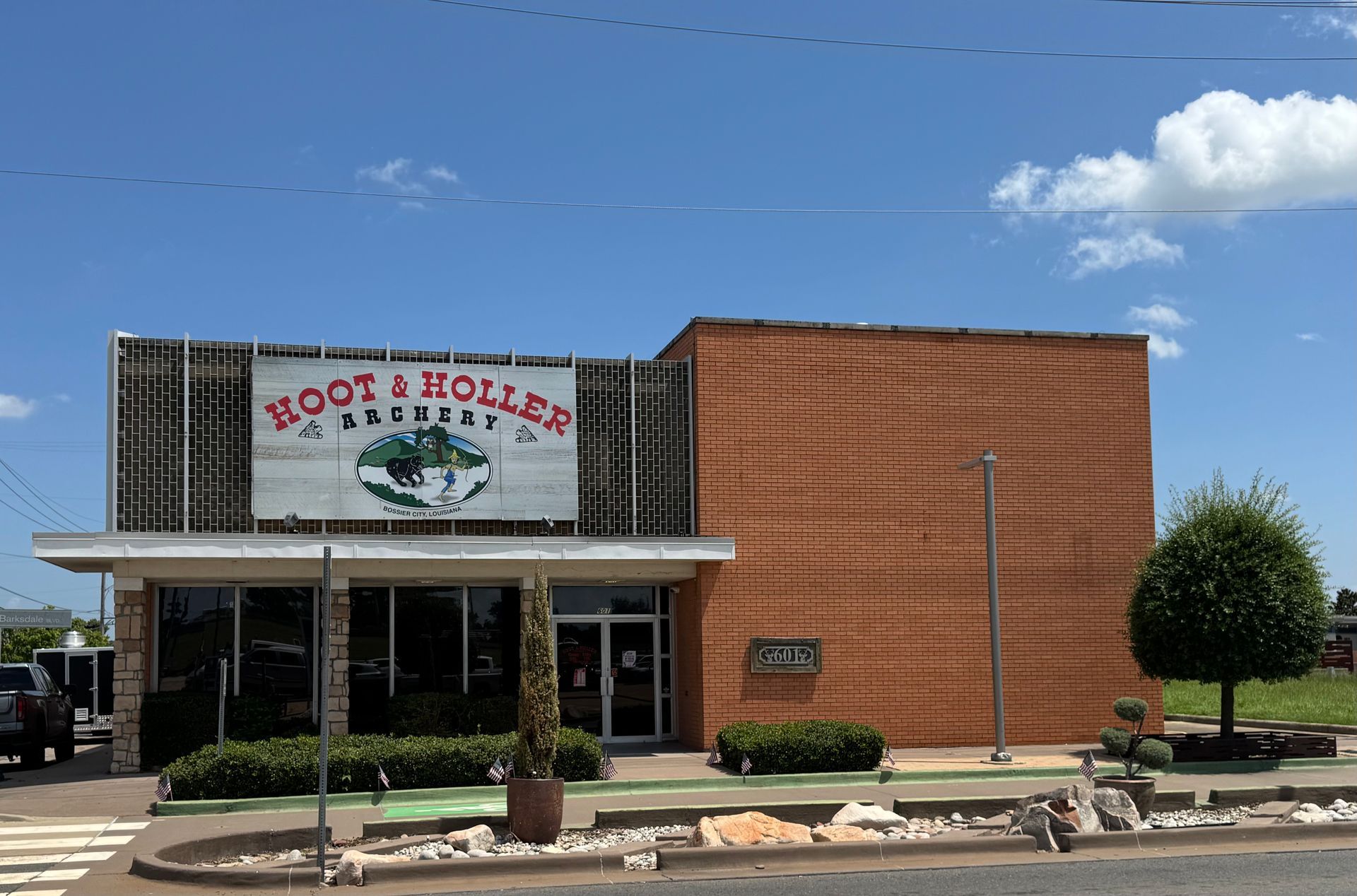 Front view of a rustic storefront with a wooden sign under a clear blue sky