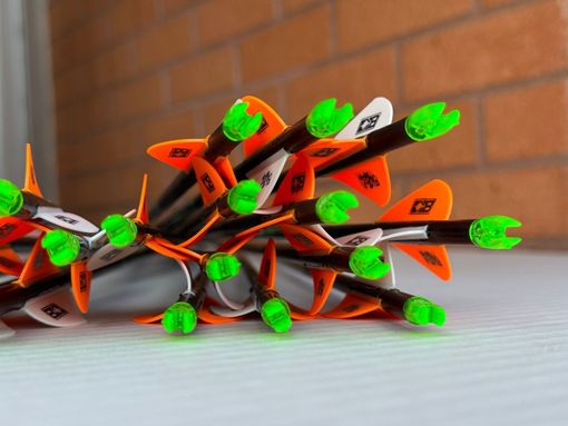 Orange and black handmade craft with green tips, arranged in a spiky bundle on a white surface.