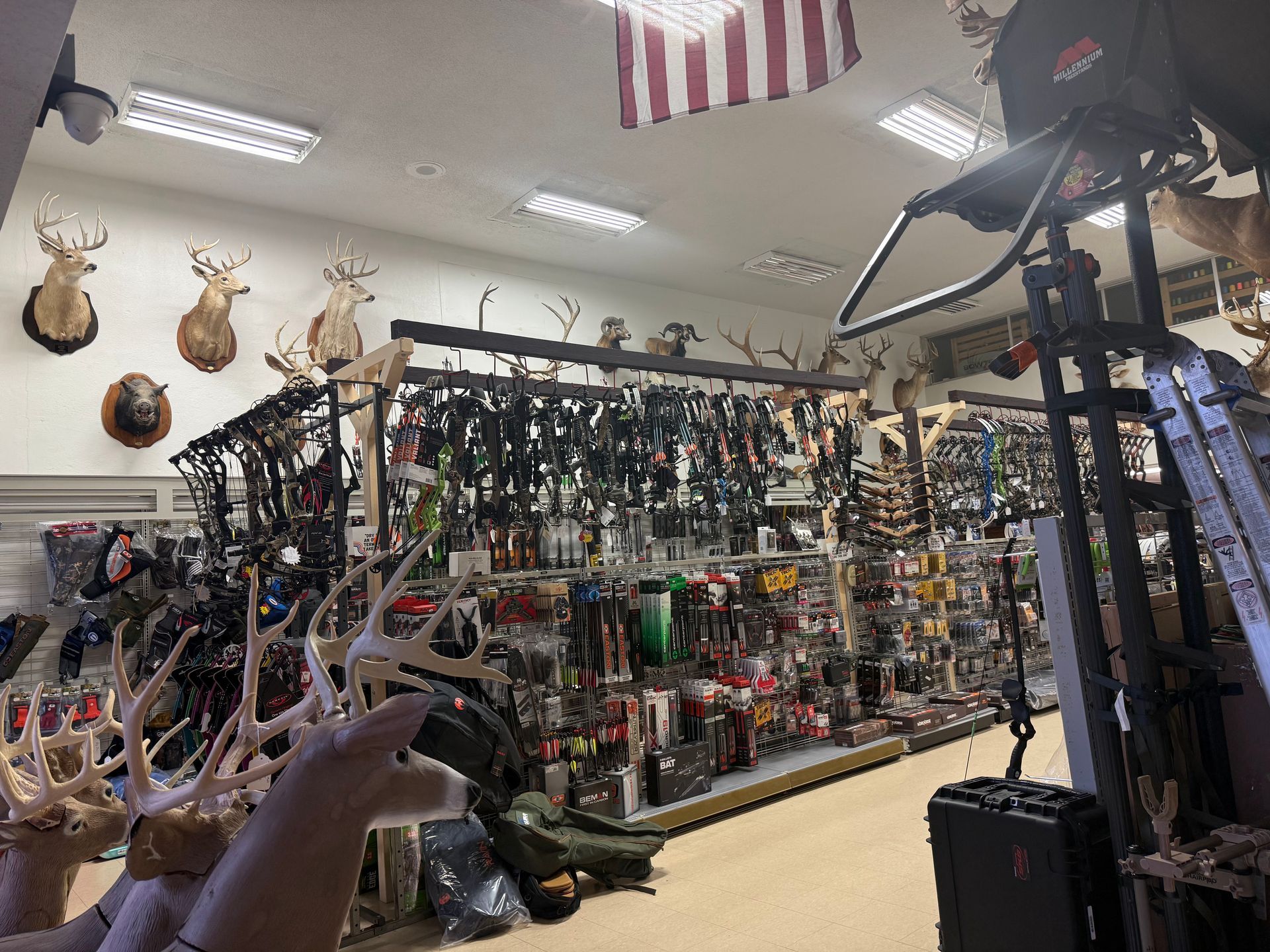 Indoor archery and hunting supply store with rows of bows, accessories, and mounted deer heads.