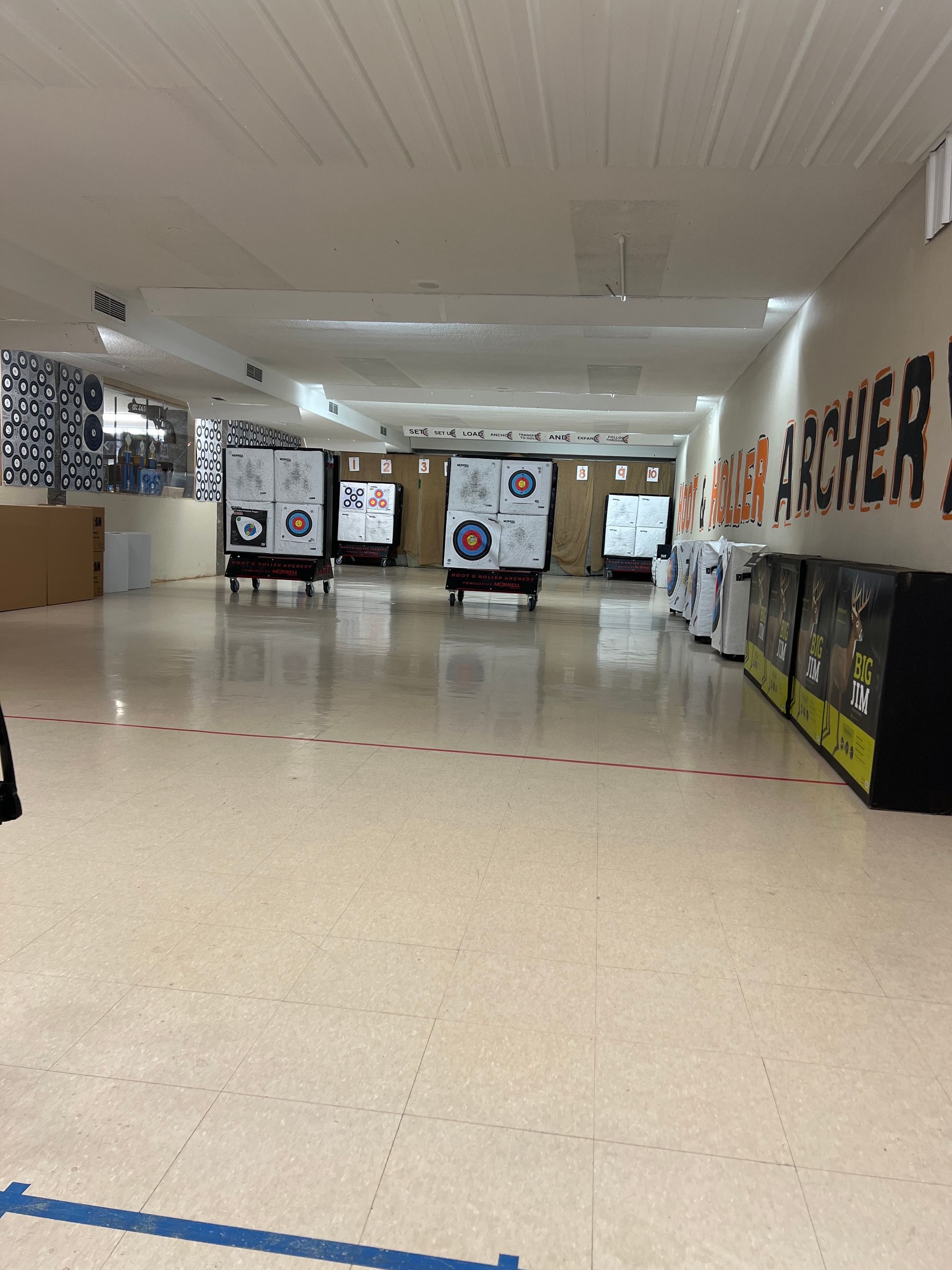 Empty school hallway with poster boards and fluorescent lights, beige tile floor and white ceiling