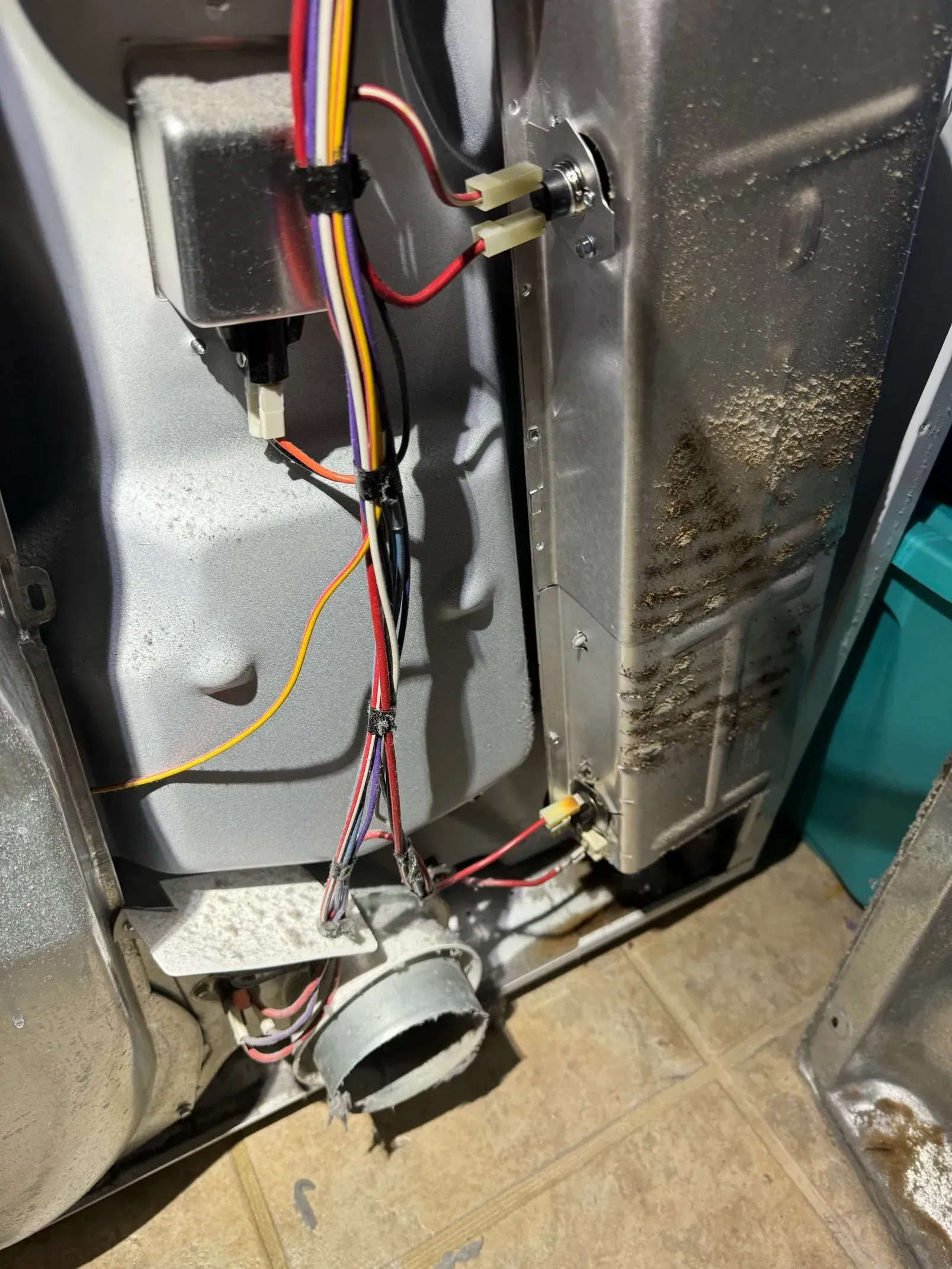 A dirty washer and dryer with a lot of wires coming out of it.