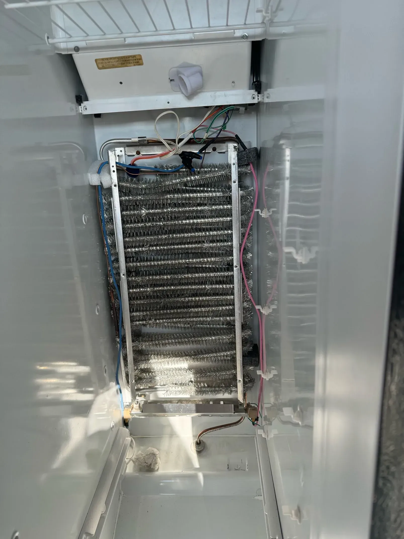 The inside of a refrigerator with a broken ice maker.