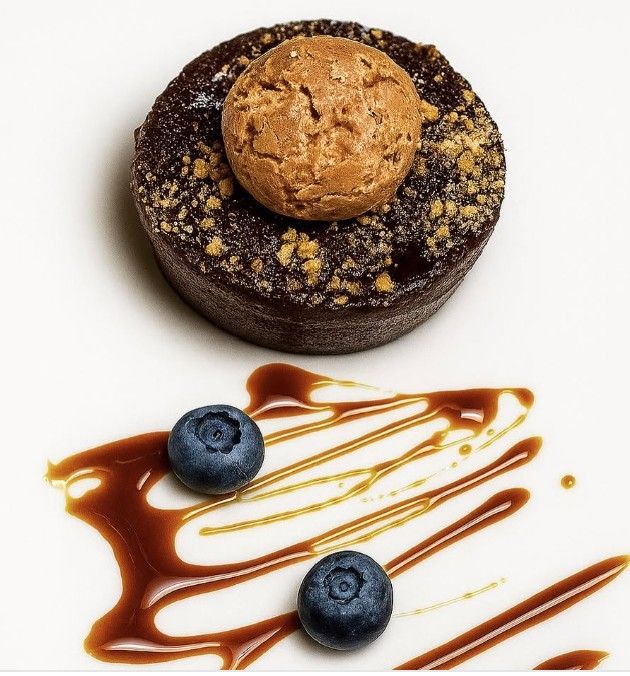 Dessert al cioccolato con biscotti e glassa al caramello, mirtilli su piatto bianco.