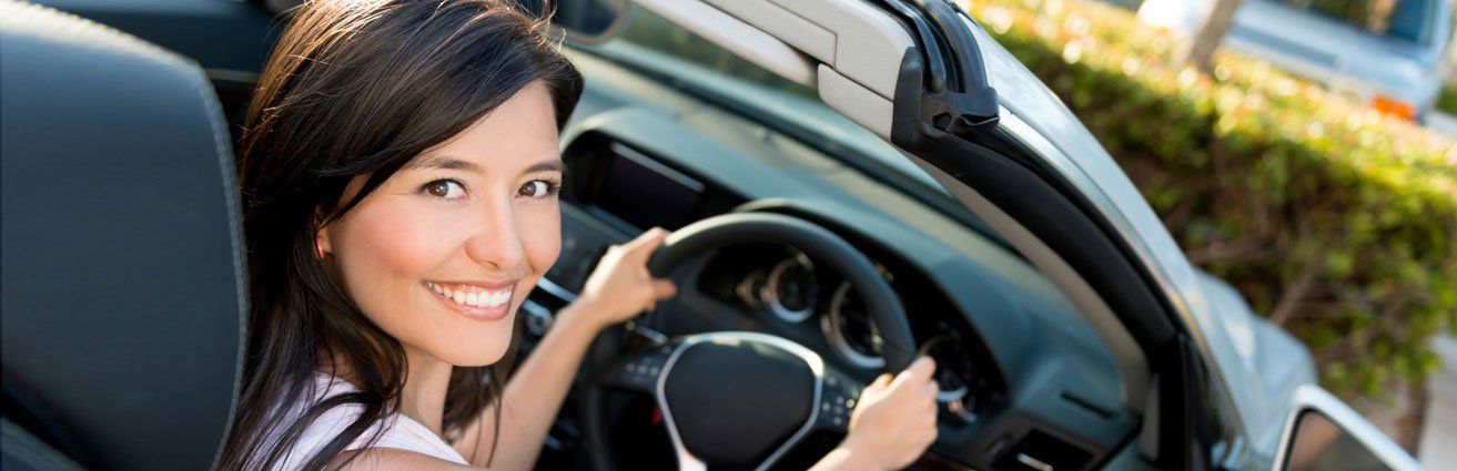 A woman is sitting in the driver 's seat of a car.