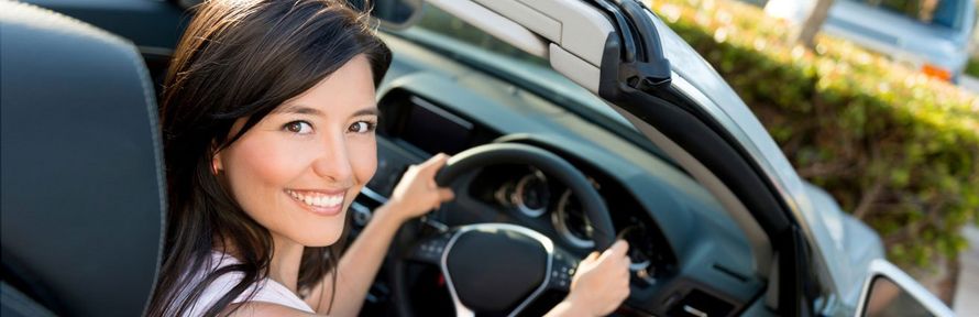 A woman is sitting in the driver 's seat of a car.