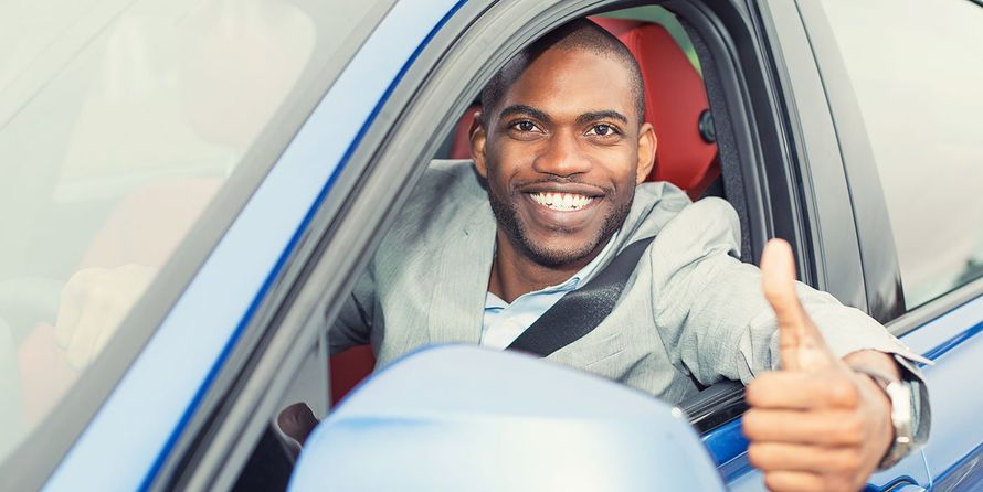 A man is giving a thumbs up while sitting in a car.