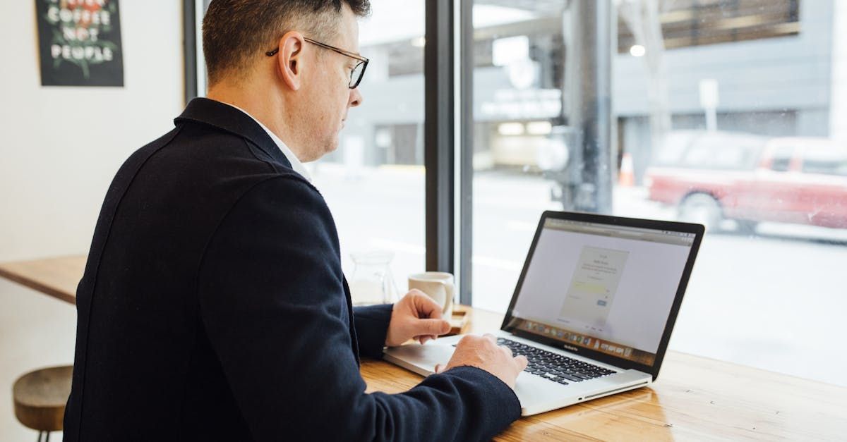 A man is sitting at a table using a laptop computer.