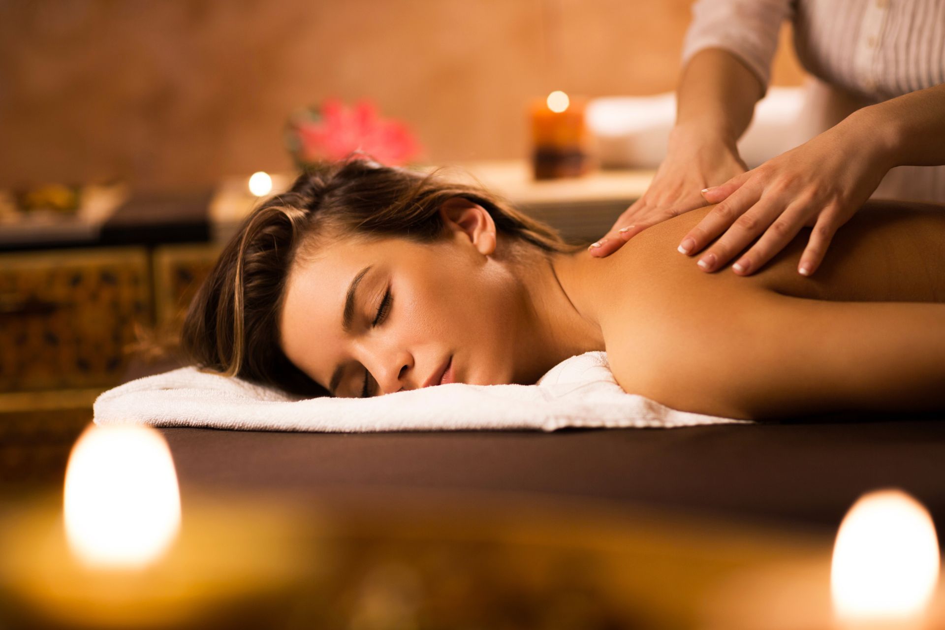 Person receiving a back massage. Hands massaging the back of a woman lying face down on a massage table.