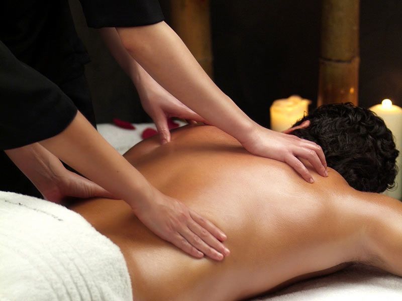Hands massaging another hand, likely in a spa setting, with soft lighting.