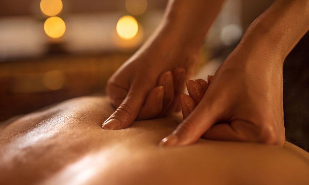 Hands massaging a person's shoulder, close-up. Focus on the shoulder, showing skin and the hands.