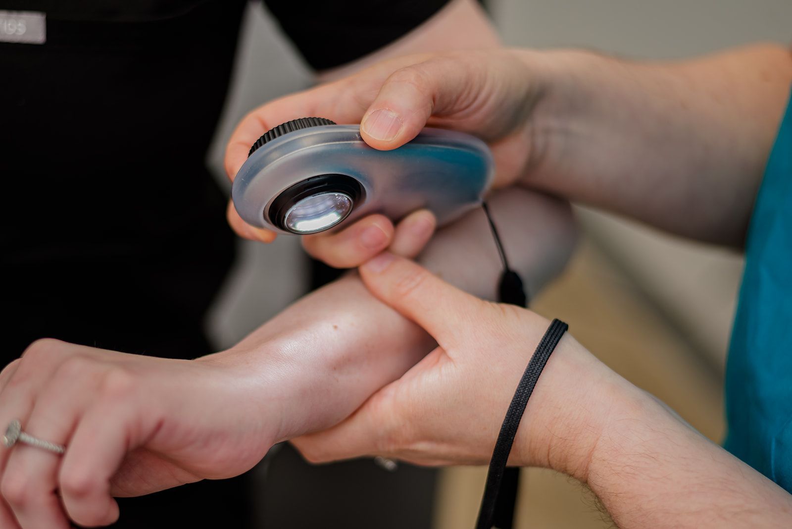 Device to examine skin held in dermatologist's hand. Assessing mole/lesion on a patient's arm.