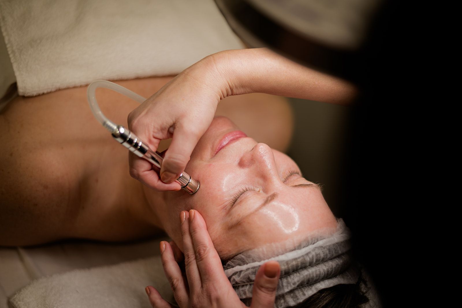 Woman receiving a microdermabrasion facial in a spa setting.