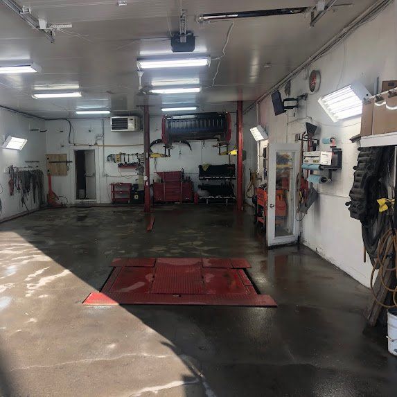 Intérieur vide d'un atelier de réparation automobile avec ponts élévateurs, outils et fosse de service rouge au sol