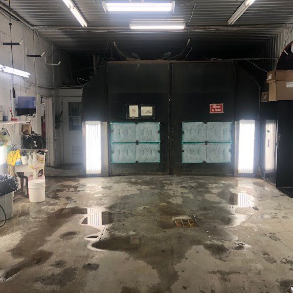 Entrepôt industriel vide avec sol en béton humide et éclairage vertical vif près de grandes portes sombres