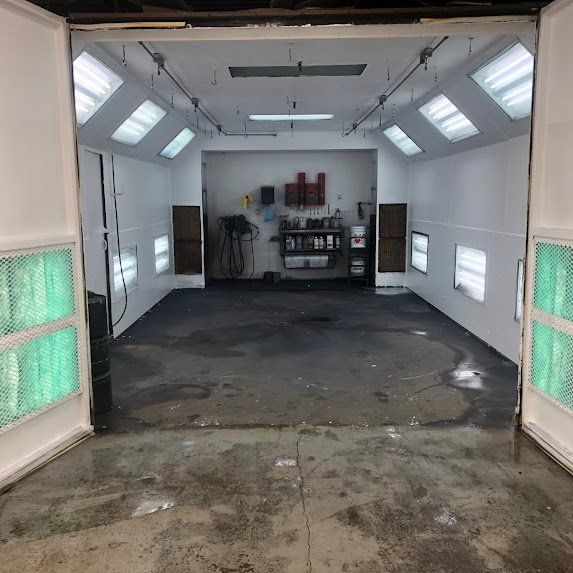 Intérieur vide d'un atelier de carrosserie avec murs blancs, puits de lumière et panneaux latéraux éclairés en vert
