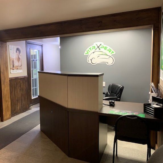 Bureau d'accueil vide dans un hall d'immeuble de bureaux lambrissé, avec un logo mural et une chaise.