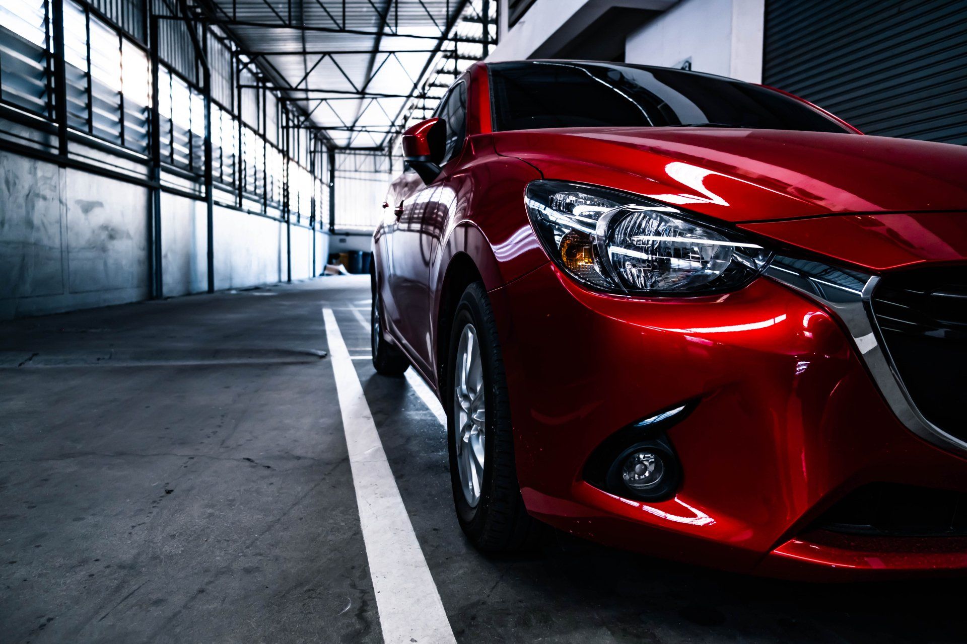 Voiture rouge garée dans un garage industriel lumineux, gros plan sur l'avant