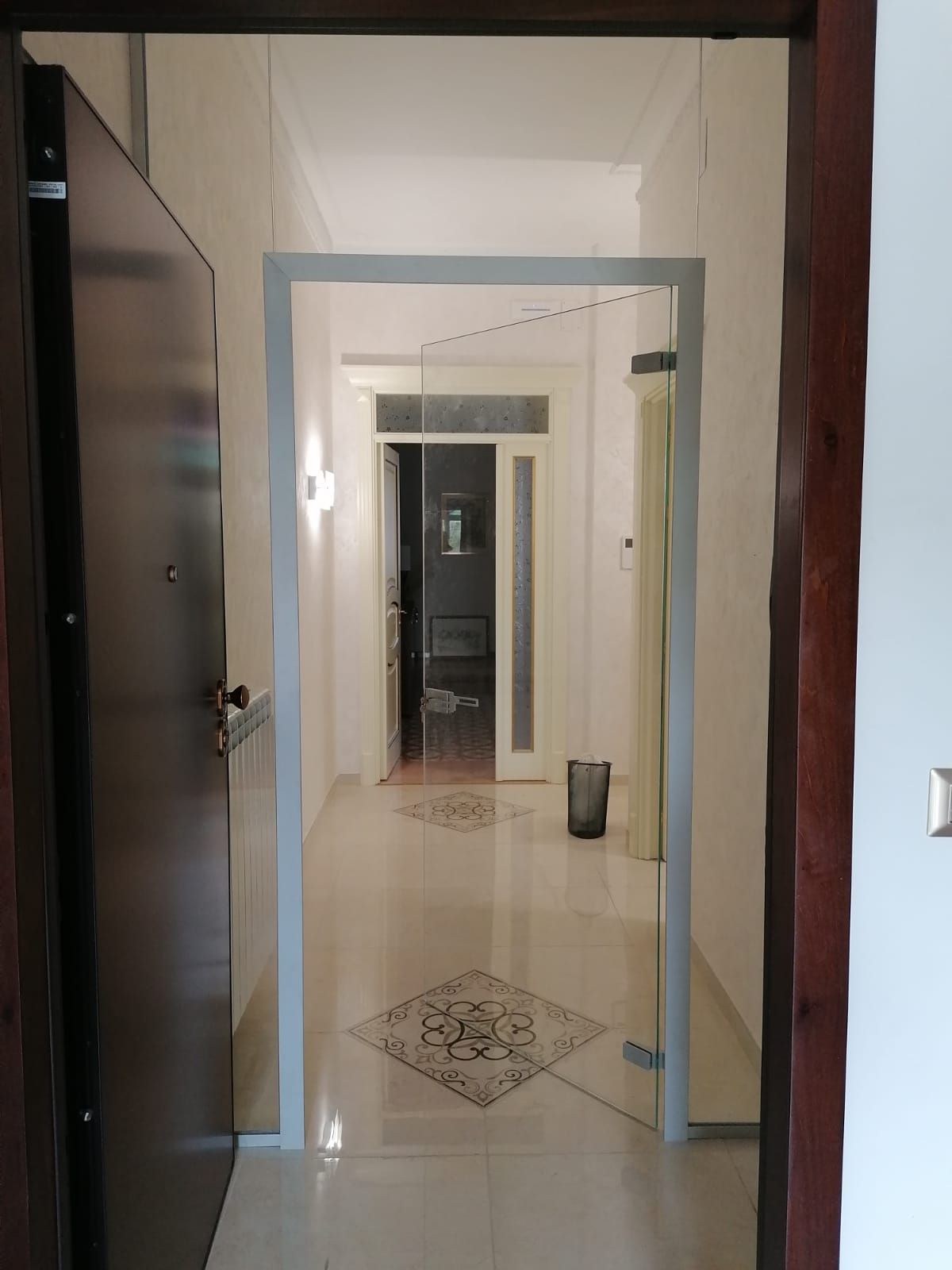 Corridoio con parete divisoria in vetro e porta che conduce a uno spazio interno.