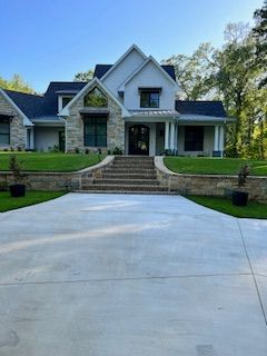 Modern two-story house with stone facade, white siding, and long concrete driveway.