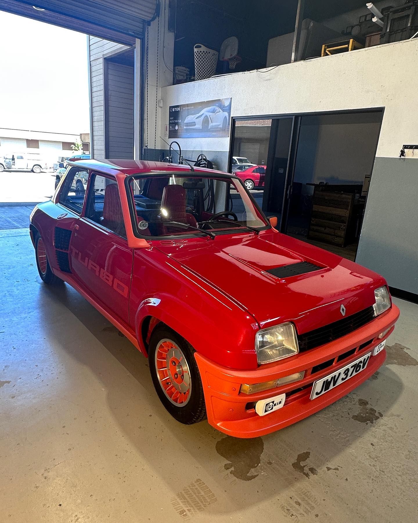 A red and orange car is parked in a garage.
