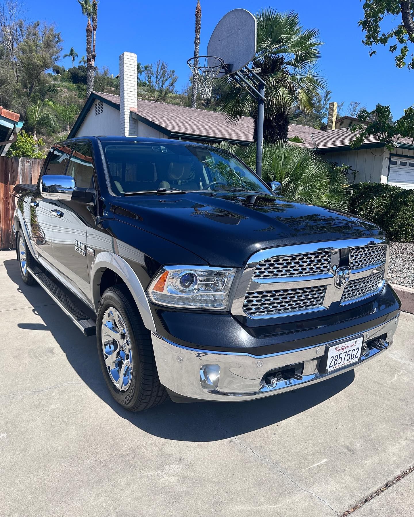 A black dodge ram truck is parked in a driveway in front of a house.