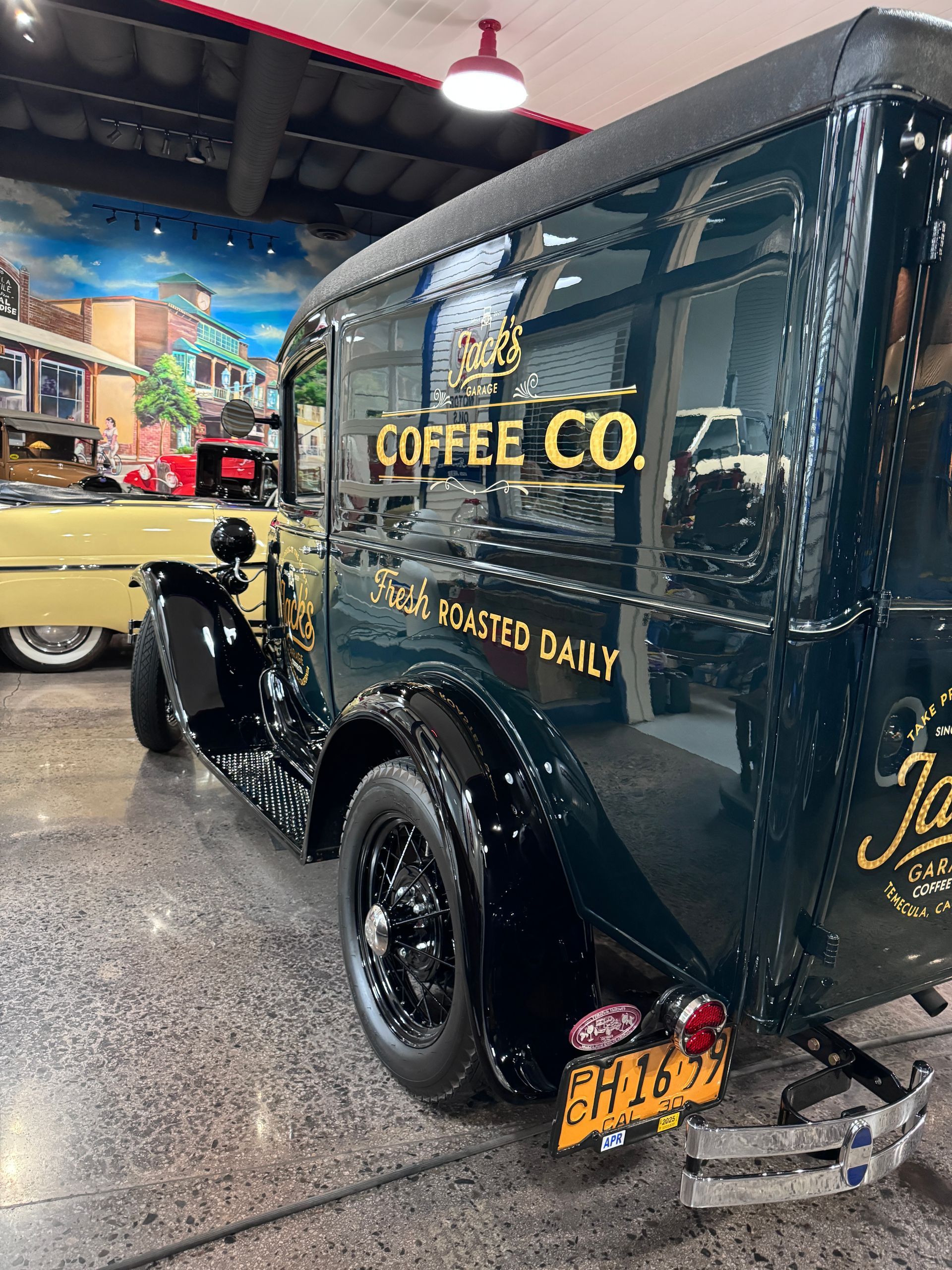 A vintage coffee co. van is parked in a garage.