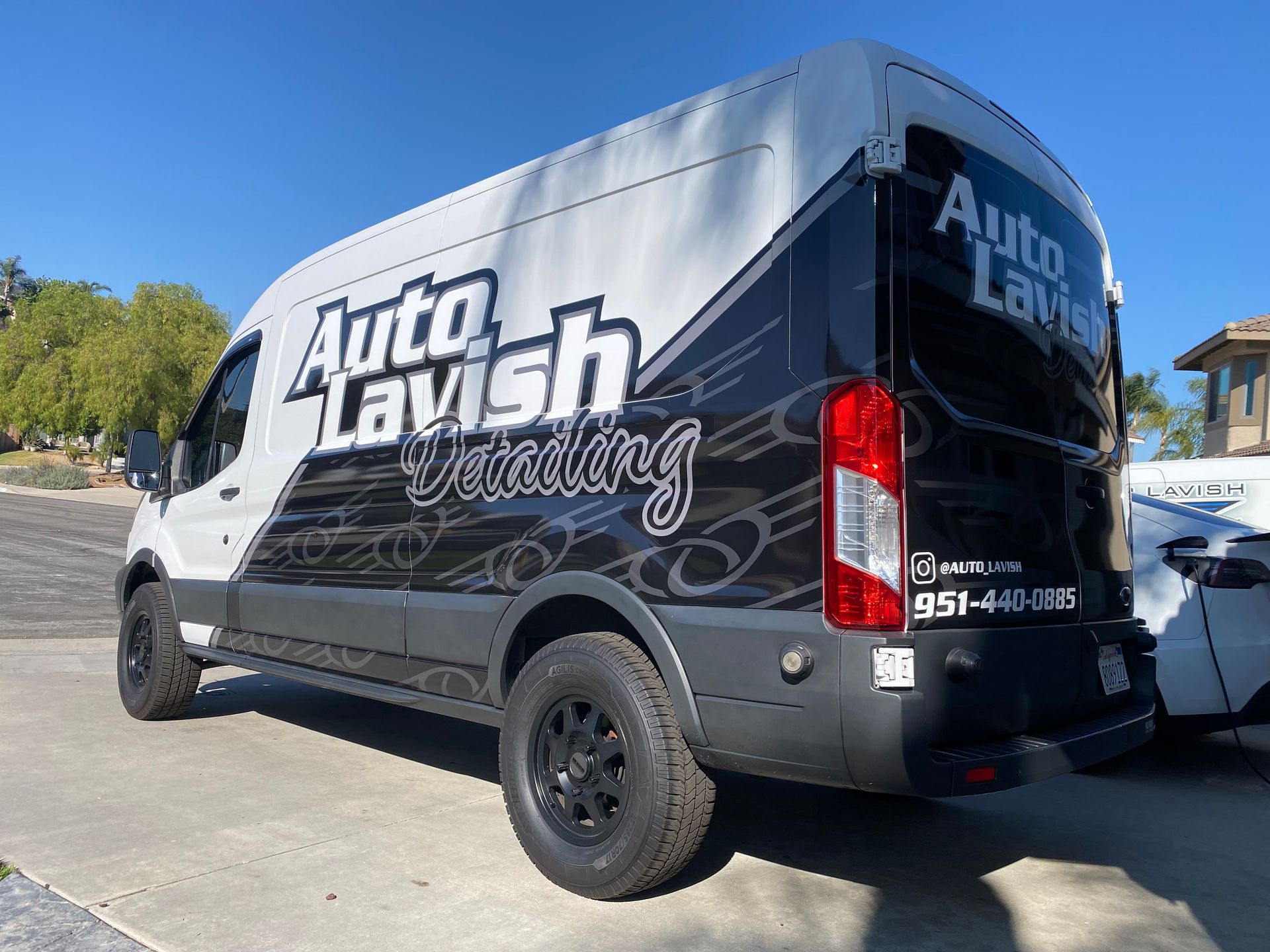 A black and white van is parked on the side of the road.