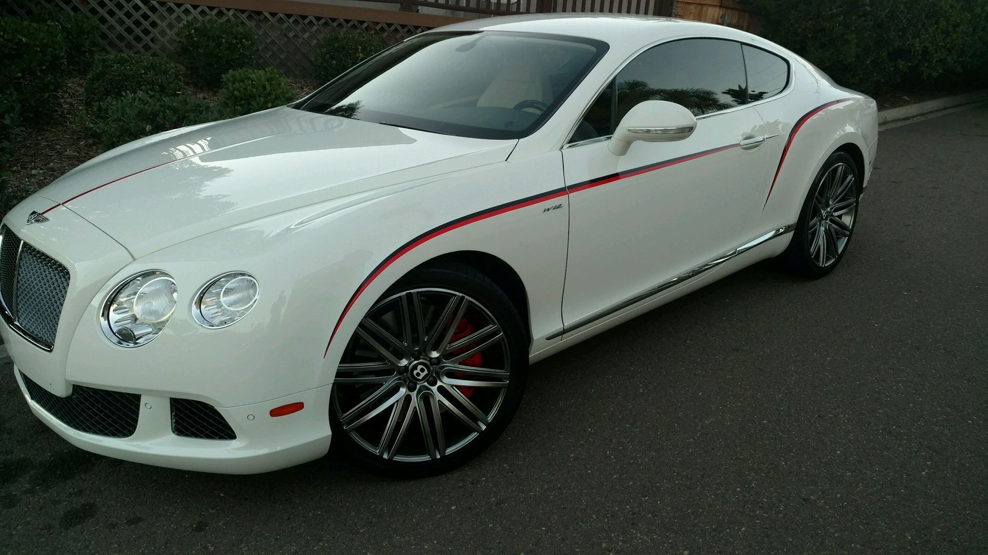 A white bentley is parked on the side of the road