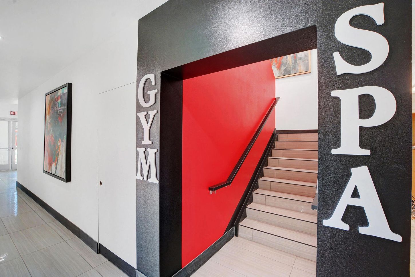 Hallway with gym/spa entrance. Staircase leads up from red-painted doorway. 