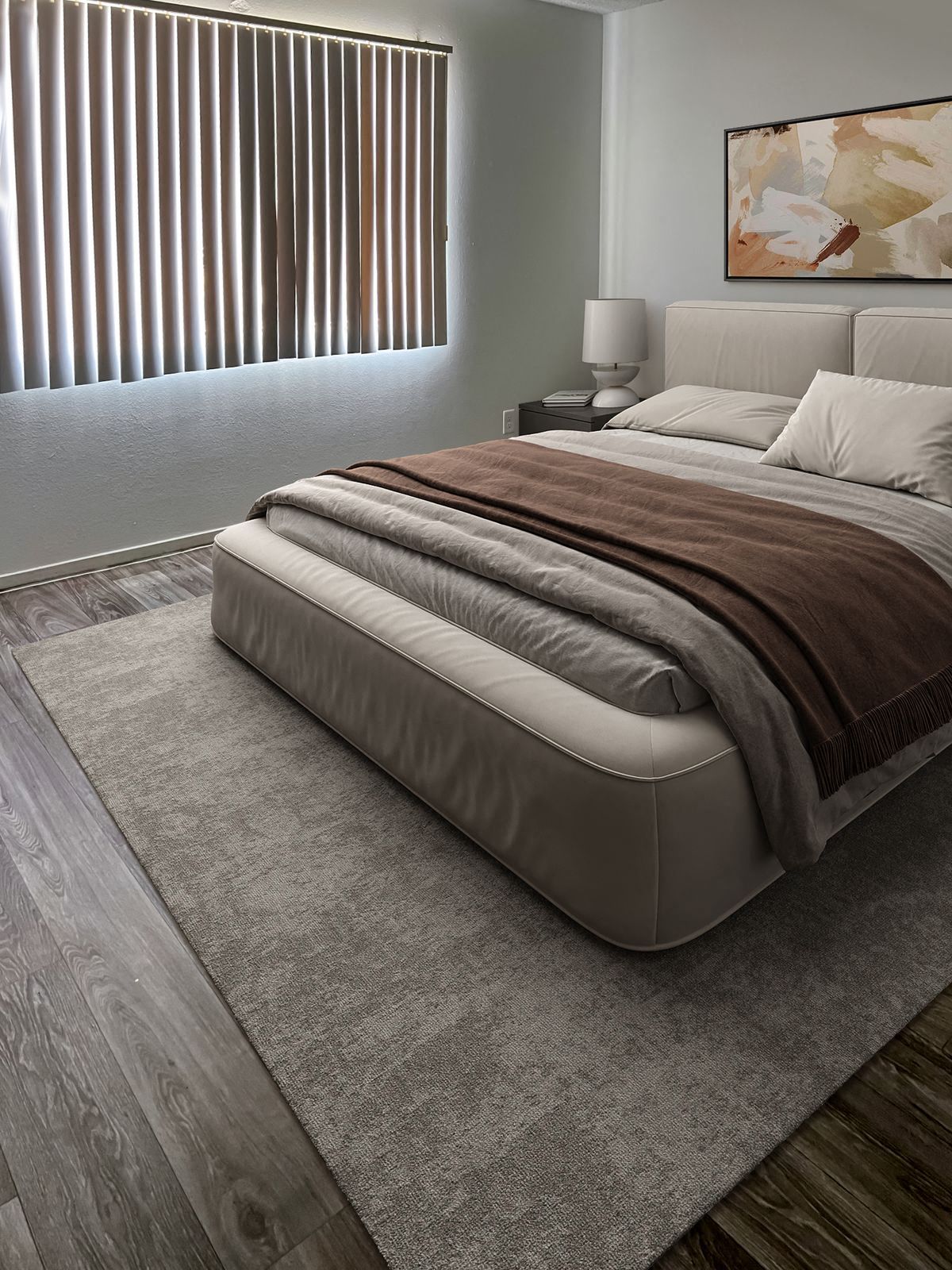 Bedroom with a bed, rug, blinds, and artwork. Neutral color scheme; natural light.