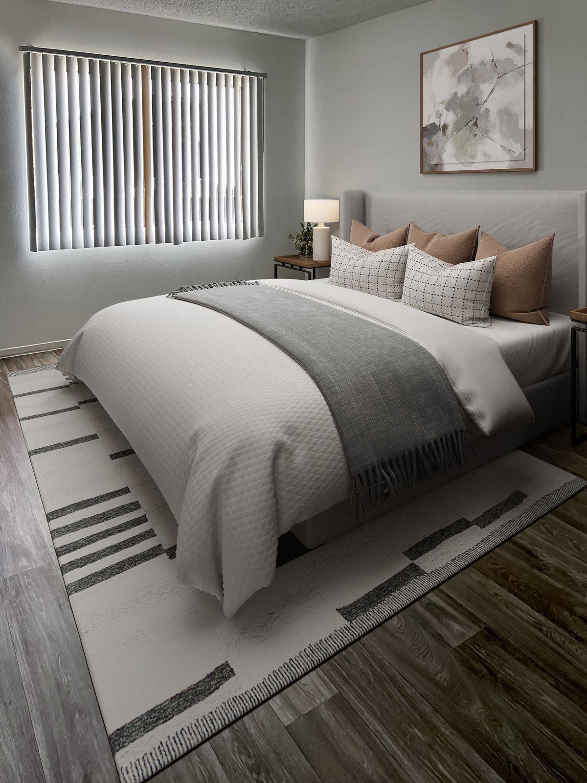 Bedroom with a bed, rug, and window with blinds. The room has gray and white decor with wooden floors.