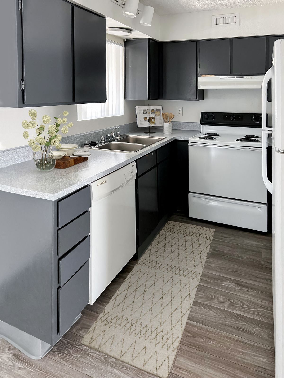 Gray and white kitchen with cabinets, appliances, and a rug.