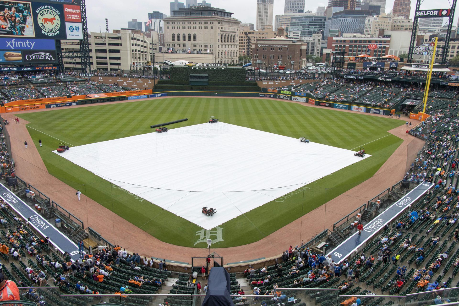 A baseball stadium with a white tarp on the field