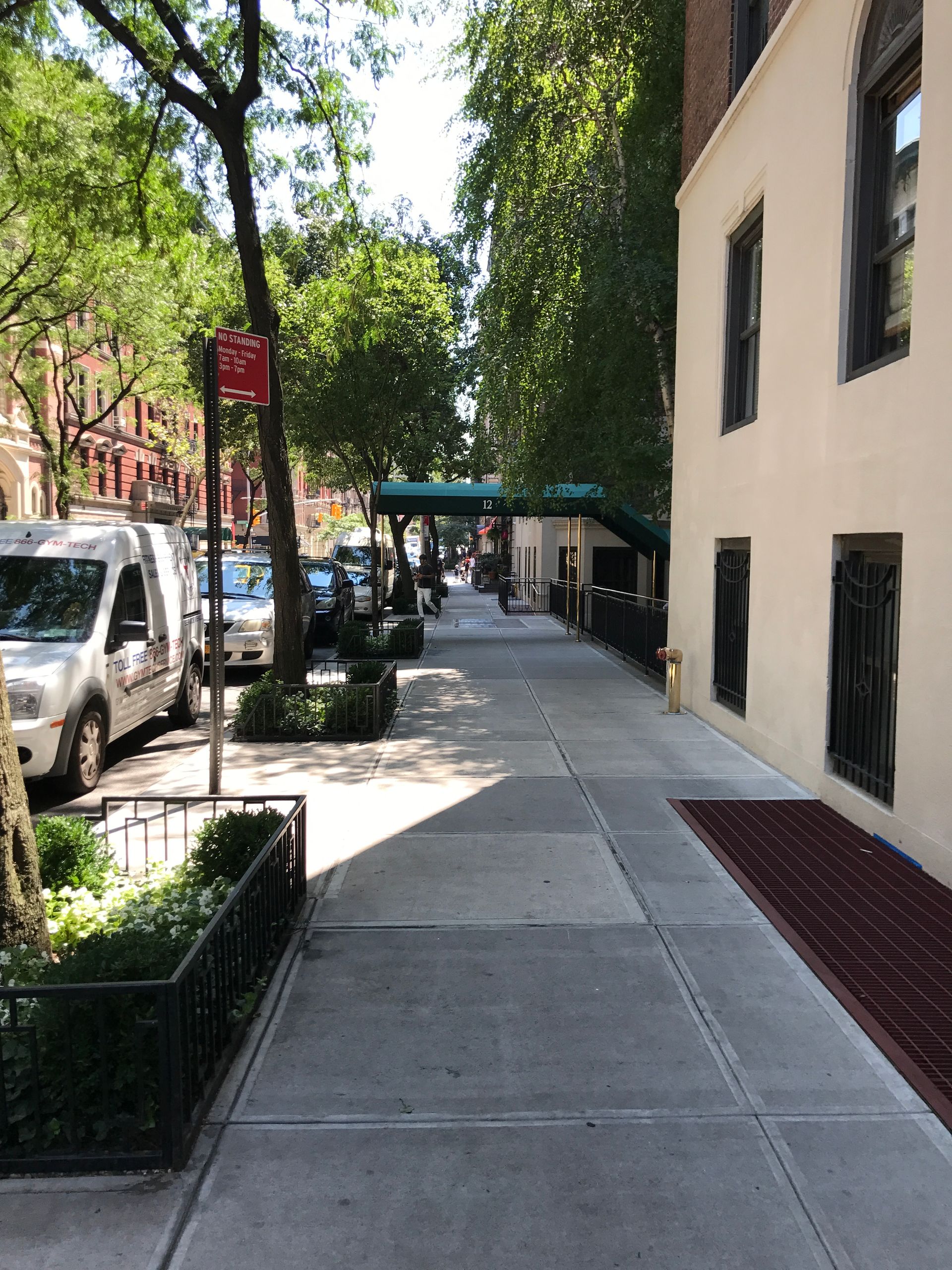 A sidewalk between two buildings with cars parked on it