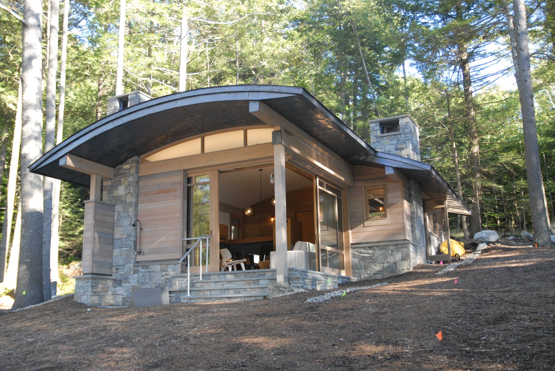 A house in the middle of a forest with a curved roof