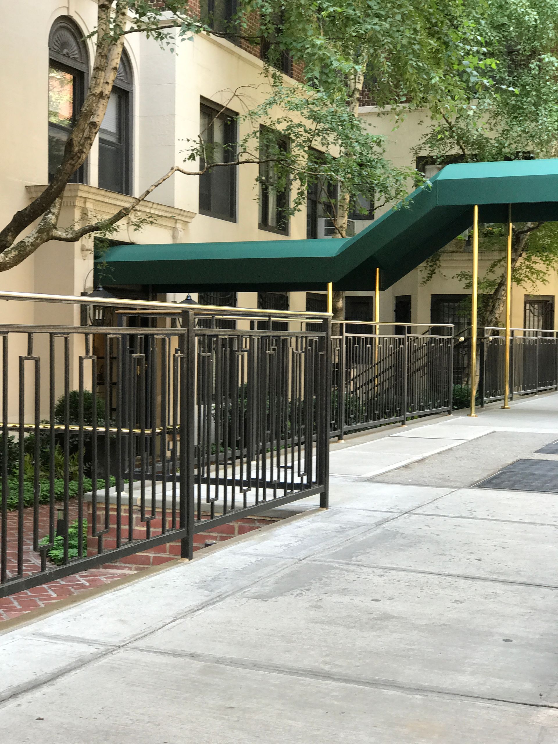 A building with a green awning on the sidewalk in front of it