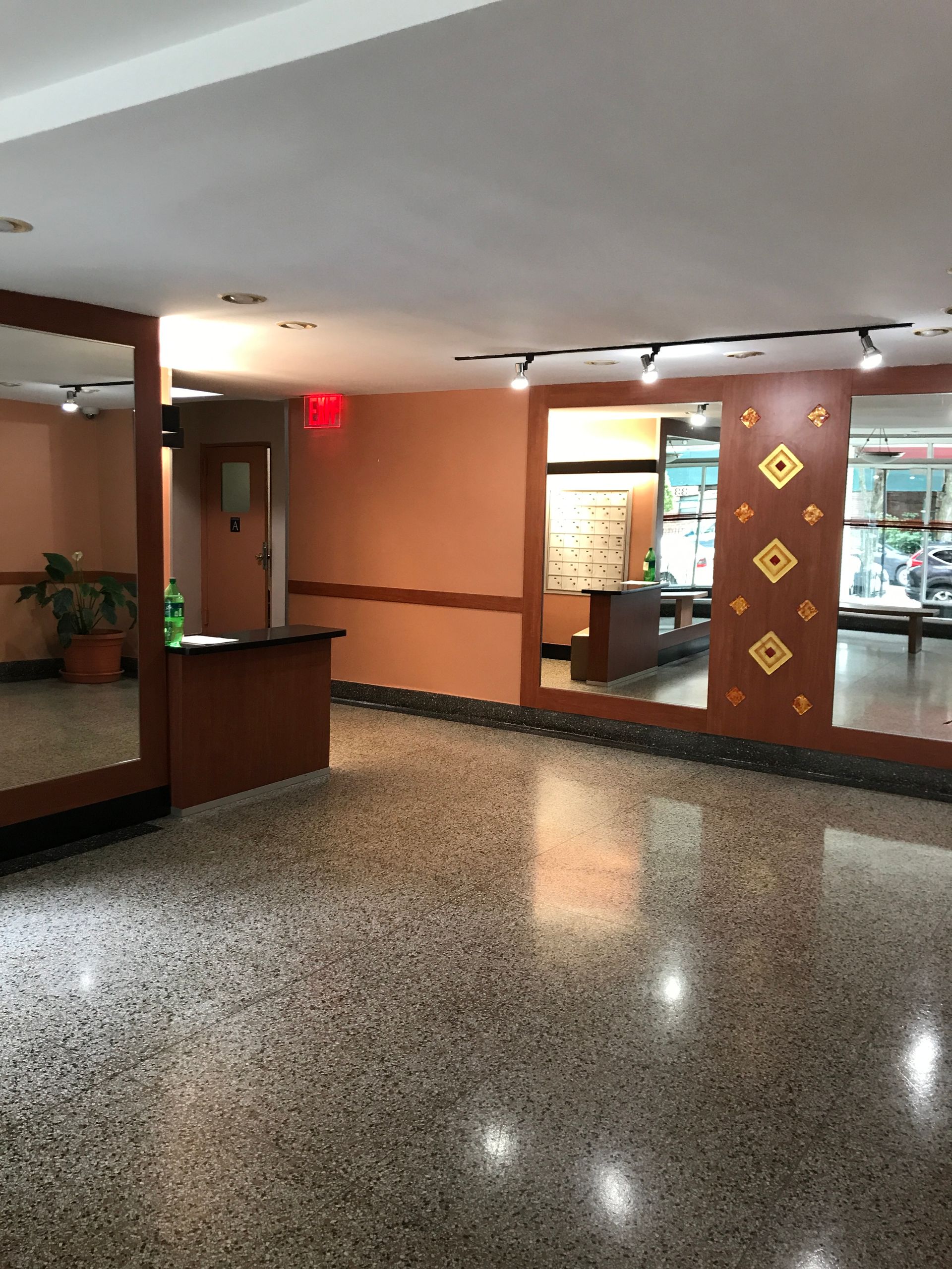 A large room with a lot of mirrors and a red exit sign