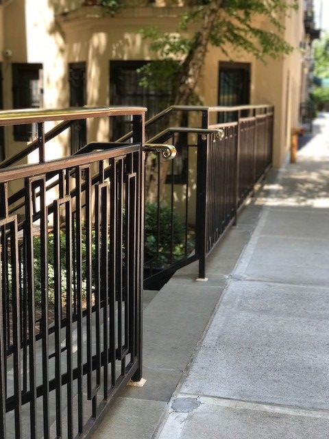 A fence along a sidewalk with a building in the background