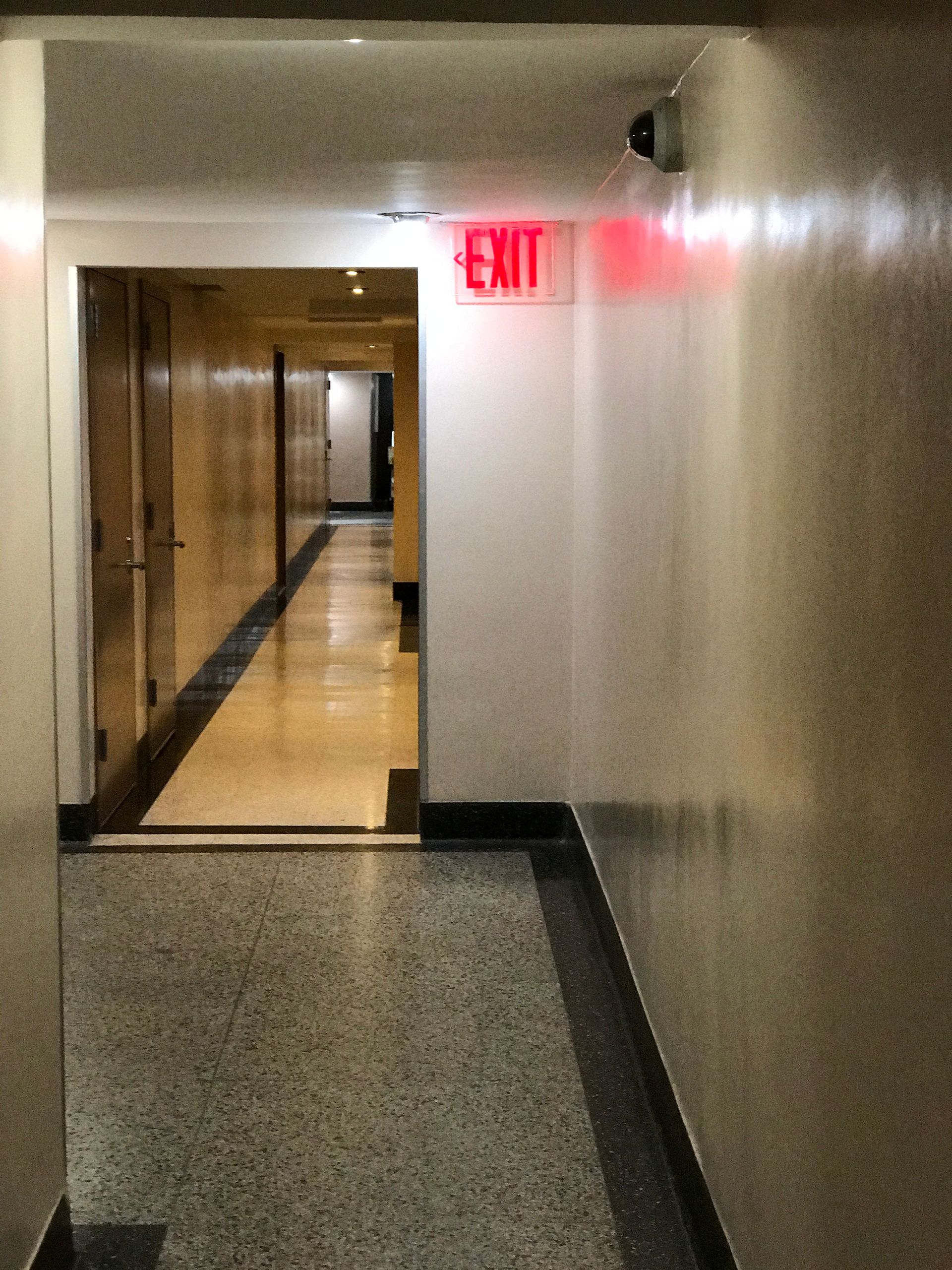 A hallway with a red exit sign on the wall