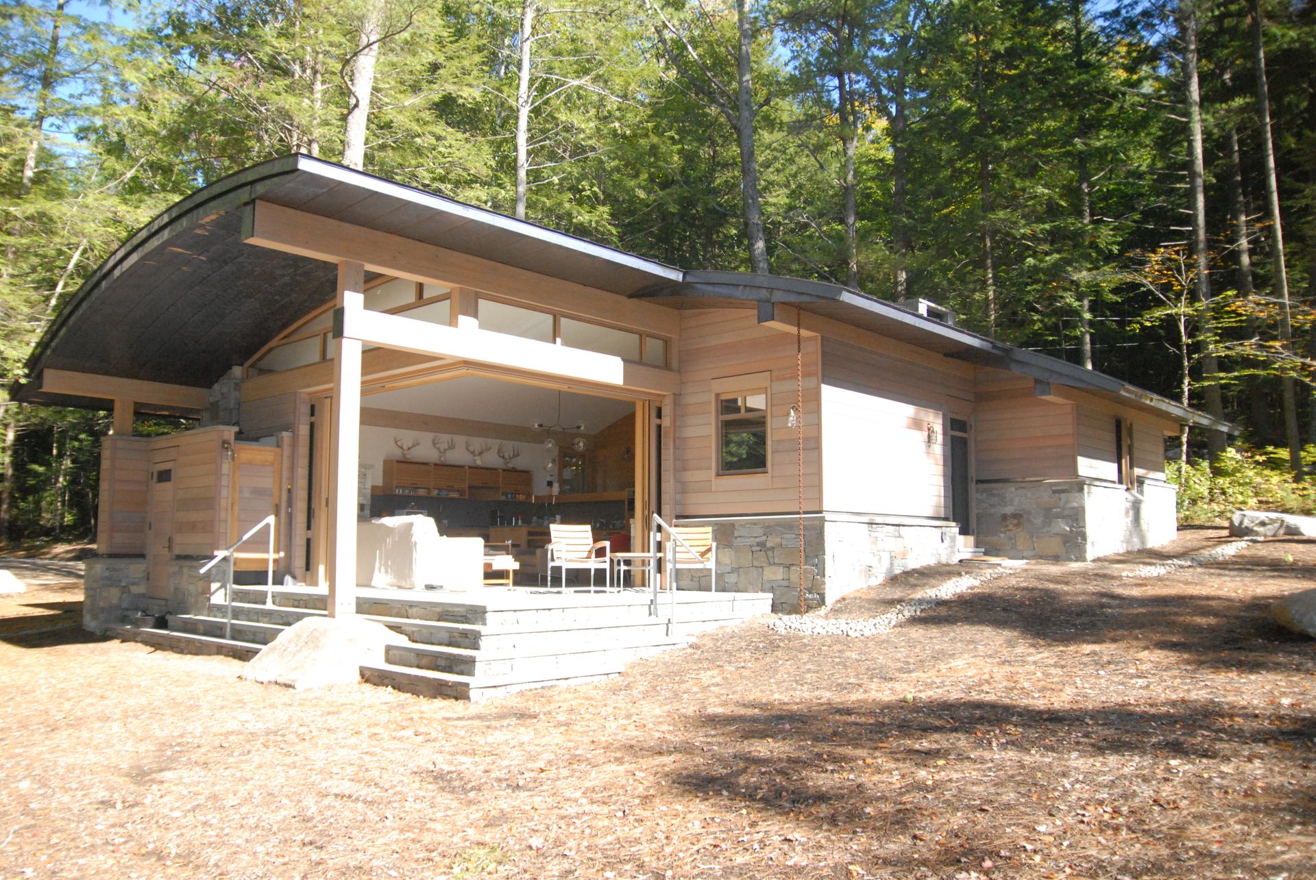 A small house with a curved roof is sitting in the middle of a forest.