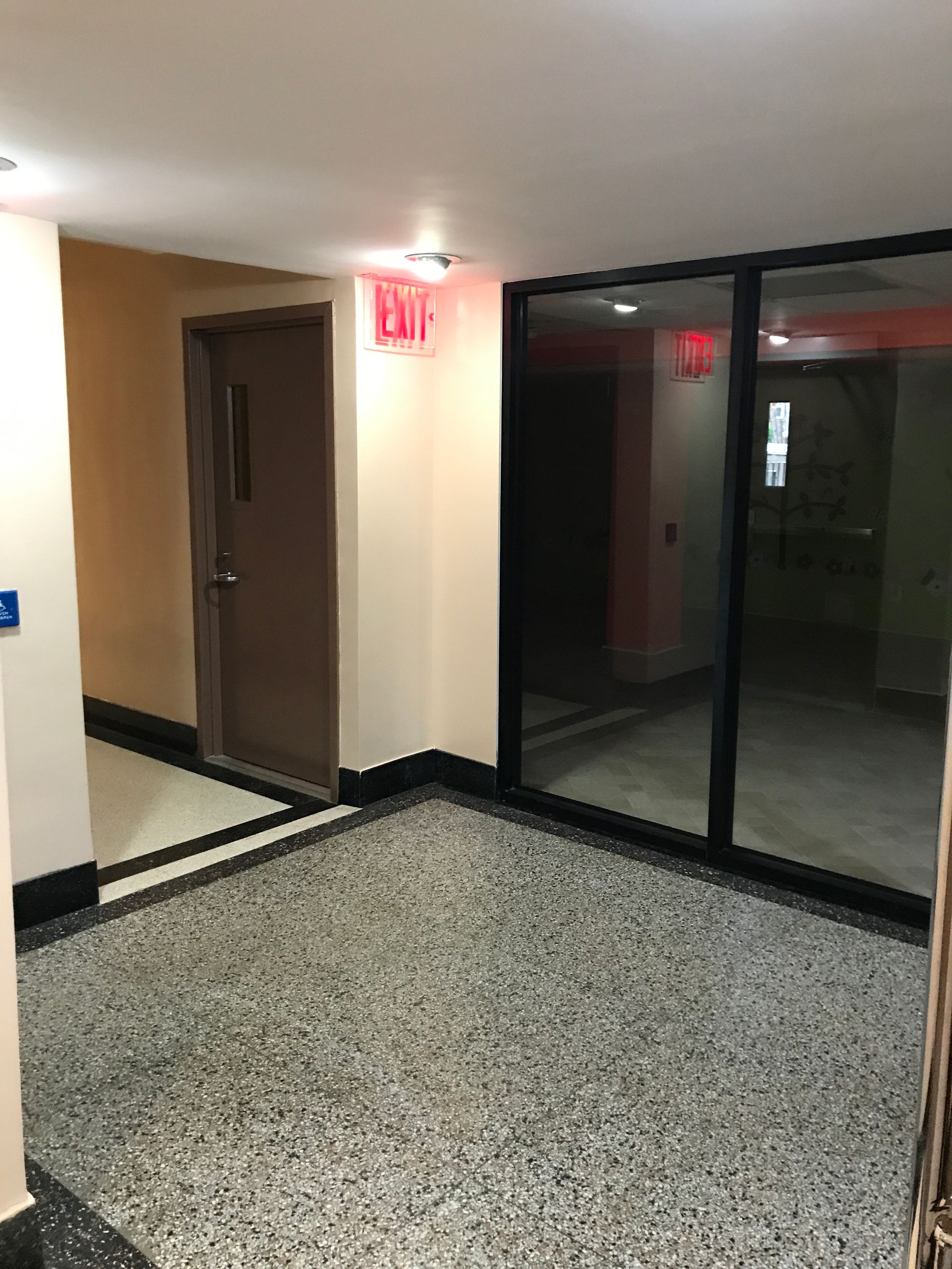 An empty hallway with a red exit sign on the wall.