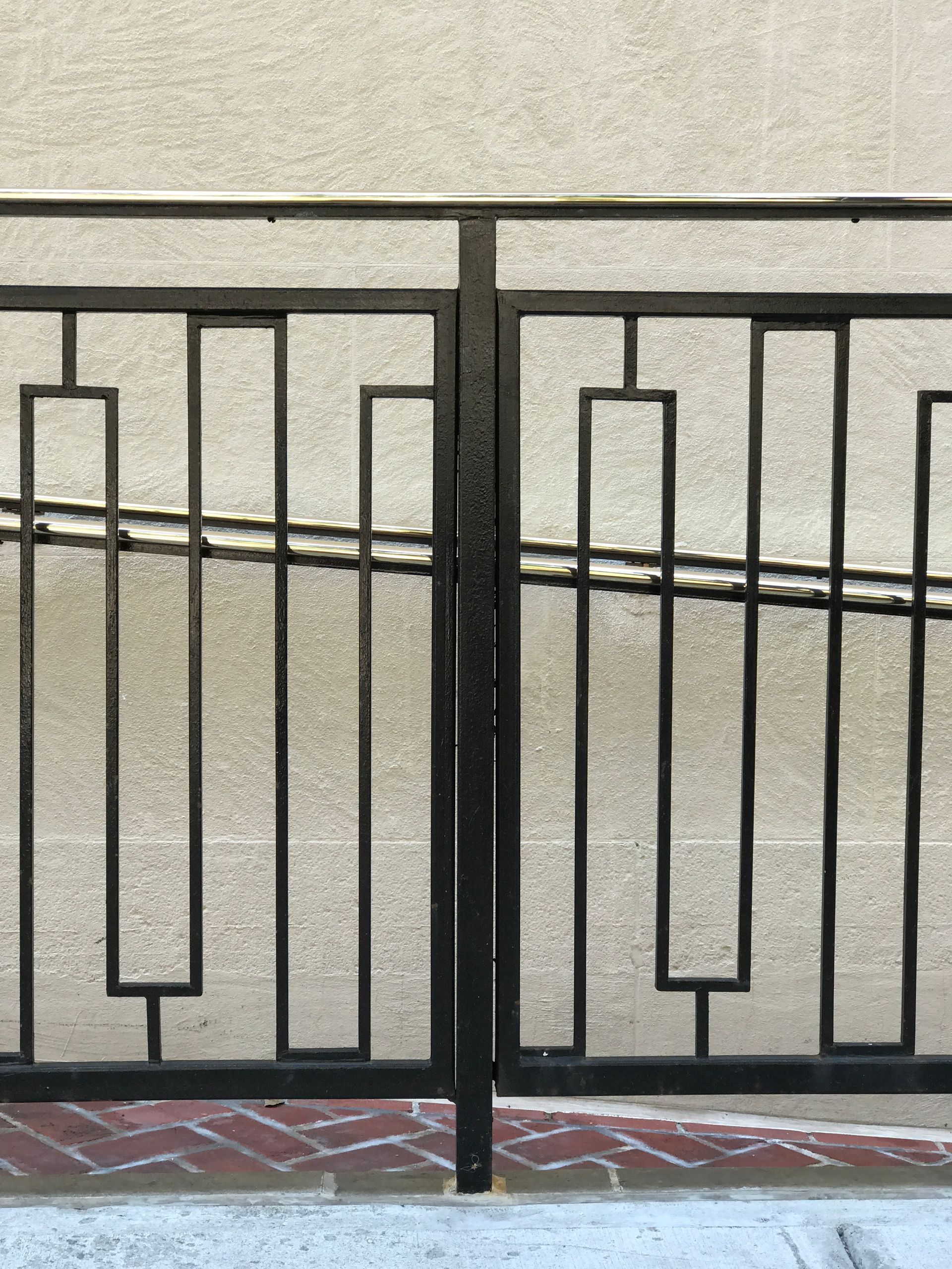 A close up of a wrought iron railing on a sidewalk.